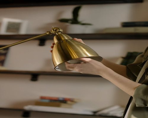 A person adjusting desk lamp in a small urban apartment